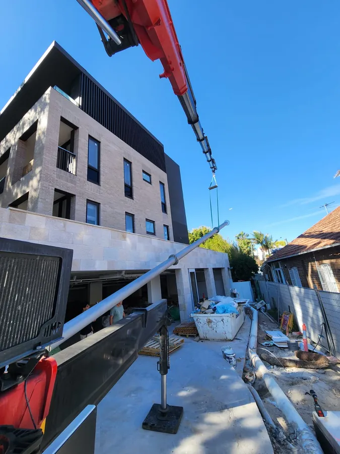 Vent shaft section being lifted into position by a truck-mounted crane on a residential building site