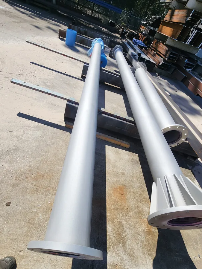 Long vent shaft sections with gusseted base flanges laid out in a yard