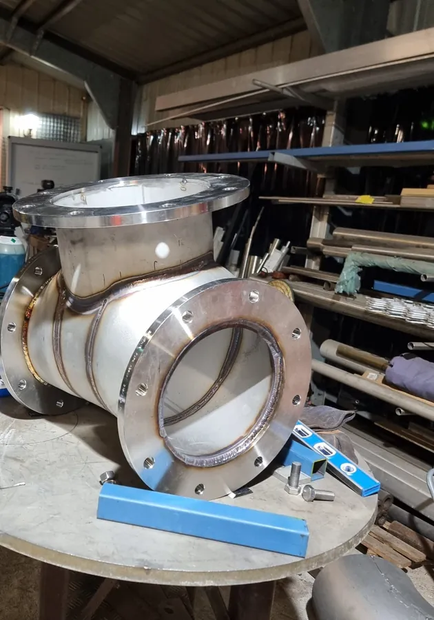 Large fabricated stainless steel flanged tee on a workshop table