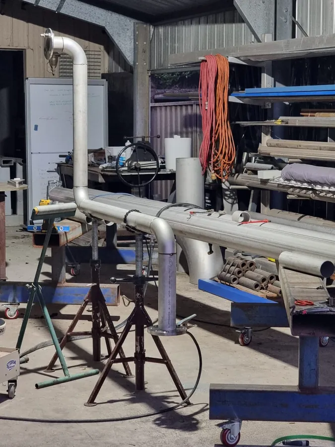 Stainless steel pipe run with welded bends on pipe stands in a workshop