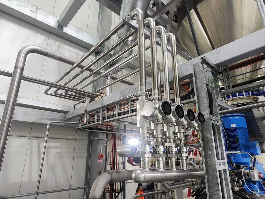 Stainless steel process pipework and valve manifold installed on a support frame in a factory